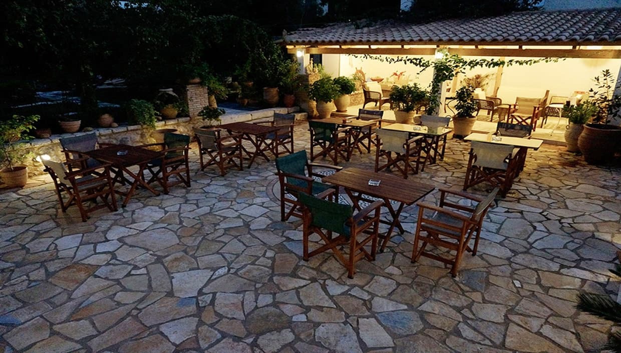 Wooden tables set out on the flagstones of the courtyard at dusk